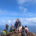 Students stand at a peak with blue sky and few clouds behind them